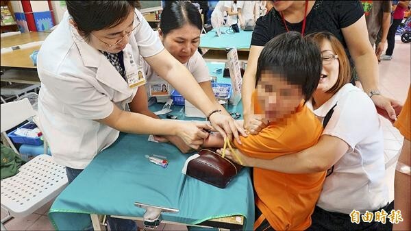 大里仁愛醫院派出十多名醫護人員免費幫啟明新生體檢，但視障生最怕抽血打針，要老師幫忙抱著安撫。（記者張軒哲攝）