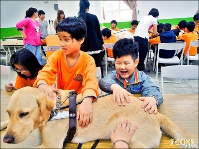 導盲犬入校園與視障生開心互動，呂岳駿（右）摸著導盲犬笑開懷。 （記者張軒哲攝）